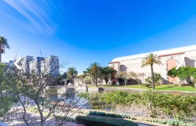 a view of a building with palm trees and a park at Modern Luxury 2BR Island Club Century City in Cape Town