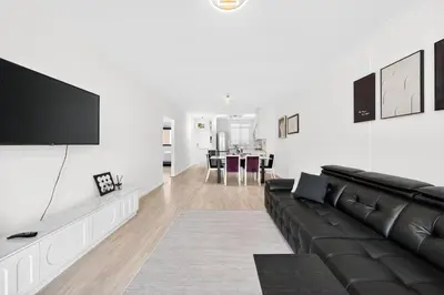 a living room with a black couch and a flat screen tv at Modern Luxury 2BR Island Club Century City in Cape Town