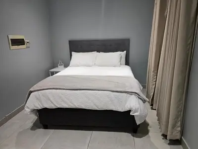 a bedroom with a large bed with white sheets at Rachel`s Apartments - Stepney Crescent in Cape Town
