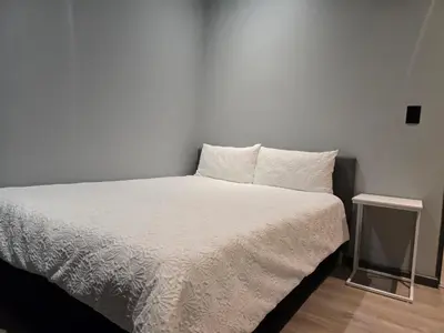 a bed in a room with a white wall at Rachel`s Apartments - Stepney Crescent in Cape Town