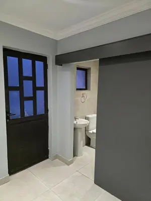 a bathroom with a black door and a toilet at Rachel`s Apartments - Stepney Crescent in Cape Town