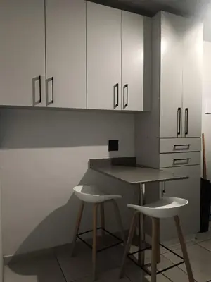 a kitchen with white cabinets and two stools at Belhar Lofts in Belhar