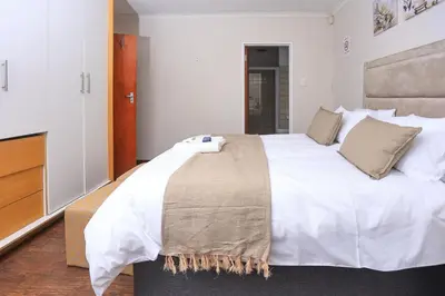 a bedroom with a large white bed and a dresser at African Oasis Morrocco in Somerset West