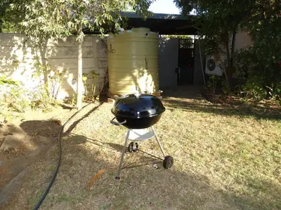 a charcoal grill on a stand in a yard at African Oasis Cameroon in Somerset West