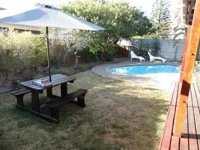 a picnic table with an umbrella next to a pool at African Oasis Cameroon in Somerset West