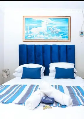 a large bed with a blue headboard and white pillows at African Oasis Cameroon in Somerset West