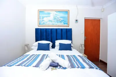 a bedroom with a large bed with a blue headboard at African Oasis Cameroon in Somerset West
