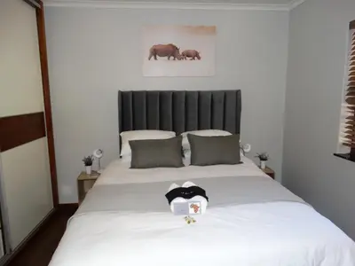 a bedroom with a large bed with a black headboard at African Oasis Kenya in Somerset West