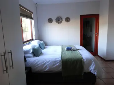 a bedroom with a bed with white sheets and blue pillows at African Oasis Zambia in Somerset West