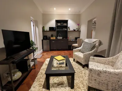 a living room with a tv and two chairs and a table at Fifty9 in Somerset West