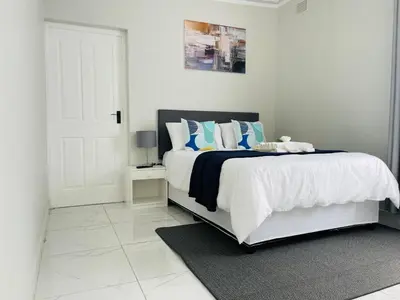 a white bedroom with a bed with blue and white pillows at Maita Corner in Monte Vista