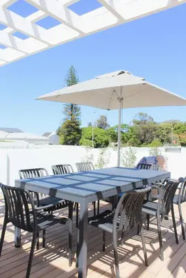 a blue table and chairs under an umbrella on a deck at Endless summer in Hermanus