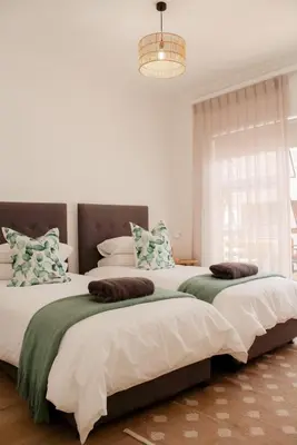 two beds in a bedroom with a chandelier at Endless summer in Hermanus