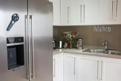 a kitchen with white cabinets and a stainless steel refrigerator at Avemore Lagratitude no6 - with full backup power in Stellenbosch