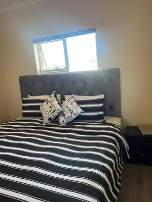 a bed with black and white striped sheets and pillows at Sleep easy at Peperboom in Kuilsrivier