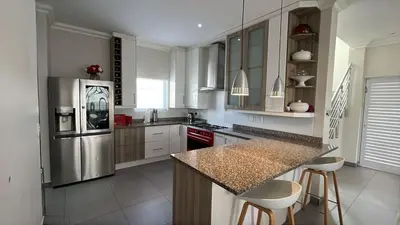 a kitchen with white cabinets and a stainless steel refrigerator at KwaNolz in Cape Town