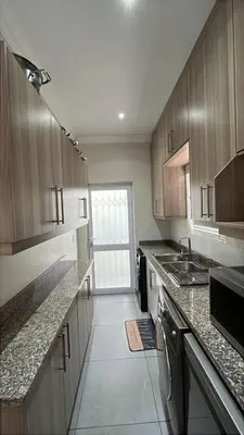 a large kitchen with wooden cabinets and a sink at KwaNolz in Cape Town