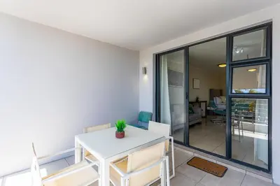 a dining room with a white table and chairs at Waterstone A202 by CTHA in Cape Town