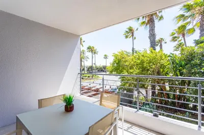a balcony with a table and a view of palm trees at Waterstone A202 by CTHA in Cape Town