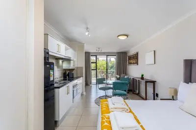a living room with a bed and a kitchen with a table at Waterstone A202 by CTHA in Cape Town