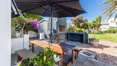 a patio with a wooden table and an umbrella at 59 Marine Hermanus in Hermanus
