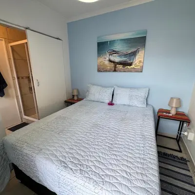 a bedroom with a bed and a picture of a boat at Sea Breeze in Strand
