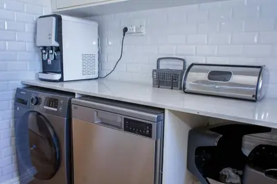 a kitchen counter with a microwave and a washer and dryer at 5BR Pool Fast Wi-Fi Walk To The Beach Pool Table in Cape Town