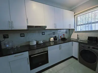 a kitchen with white cabinets and a black dishwasher at Beachwalk luxury one bedroom apartments in Cape Town