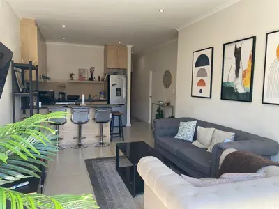 a living room with a couch and a kitchen at Elegant, Relaxing Gateway House in Cape Town in Cape Town