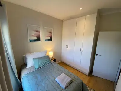 a bedroom with a bed and a white cabinet at Elegant, Relaxing Gateway House in Cape Town in Cape Town