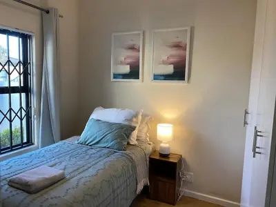 a bedroom with a bed and a lamp on a table at Elegant, Relaxing Gateway House in Cape Town in Cape Town