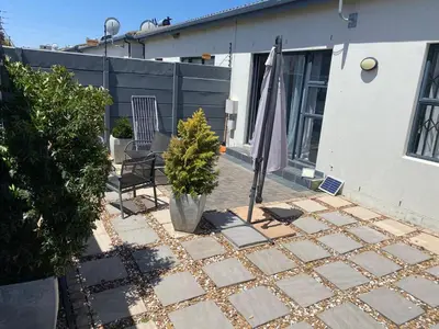 a patio with an umbrella and a chair and a table at Elegant, Relaxing Gateway House in Cape Town in Cape Town