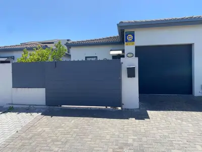 a building with a gate and a garage at Elegant, Relaxing Gateway House in Cape Town in Cape Town
