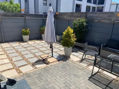 an umbrella sitting on a patio with two plants at Elegant, Relaxing Gateway House in Cape Town in Cape Town
