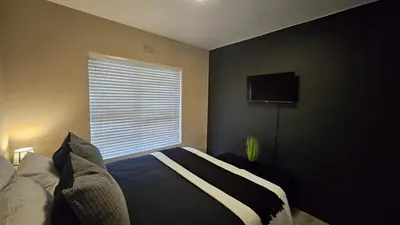 a bedroom with a bed and a window with a television at Her Sanctuary in Cape Town