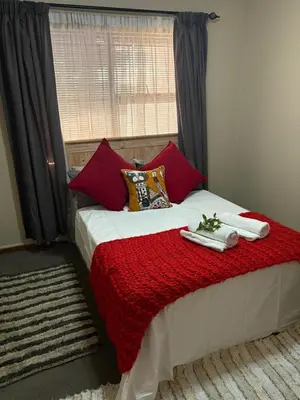 a bed with red pillows and towels on it at Waaigras in Brackenfell