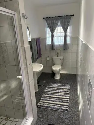 a bathroom with a toilet and a tub and a sink at Waaigras in Brackenfell