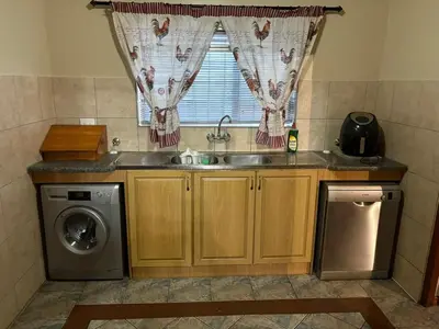 a kitchen with a sink and a washing machine at Waaigras in Brackenfell