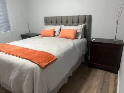 a bedroom with a large bed with two orange pillows at Oryx guest house in Oakdale