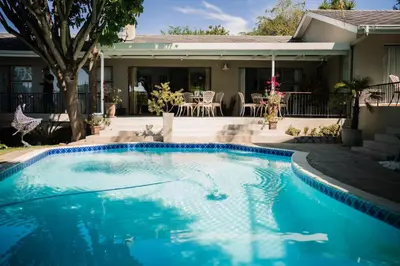 a swimming pool in front of a house at De Wingerd Wijnland Lodge in Paarl