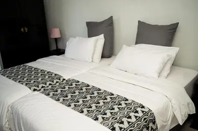 a bedroom with two beds with white sheets and pillows at De Wingerd Wijnland Lodge in Paarl