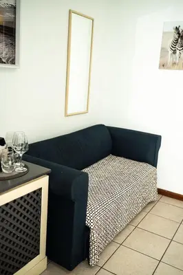 a blue couch sitting in a room with a window at De Wingerd Wijnland Lodge in Paarl