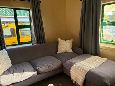 a couch sitting in a living room with a window at Peaceful coastal holiday home in Hermanus