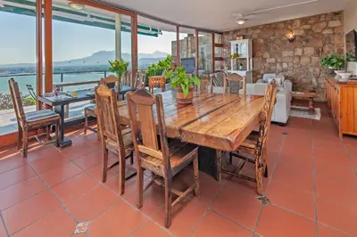a dining room with a wooden table and chairs at 18 On Kloof Guest House in Gordonʼs Bay