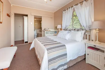 a bedroom with a large white bed and a window at 18 On Kloof Guest House in Gordonʼs Bay