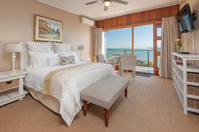 a bedroom with a bed and a view of the ocean at 18 On Kloof Guest House in Gordonʼs Bay