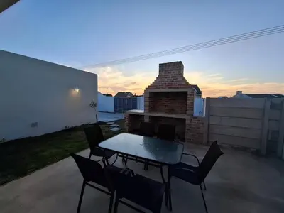 a patio with a table and chairs and a fireplace at Embrace This Planet Self-Catering Accommodation in Fisherhaven