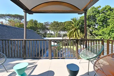 a deck with chairs and tables and a playground at Mawethu on Mead Guesthome with Covered pool and Garden in Cape Town
