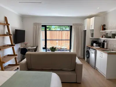 a living room with a couch and a kitchen at Protea Cottage Cozy & Private Studio in Claremont in Cape Town
