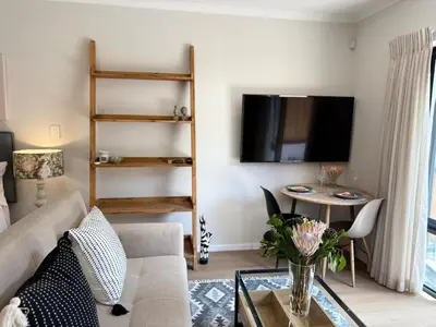 a living room with a couch and a table at Protea Cottage Cozy & Private Studio in Claremont in Cape Town